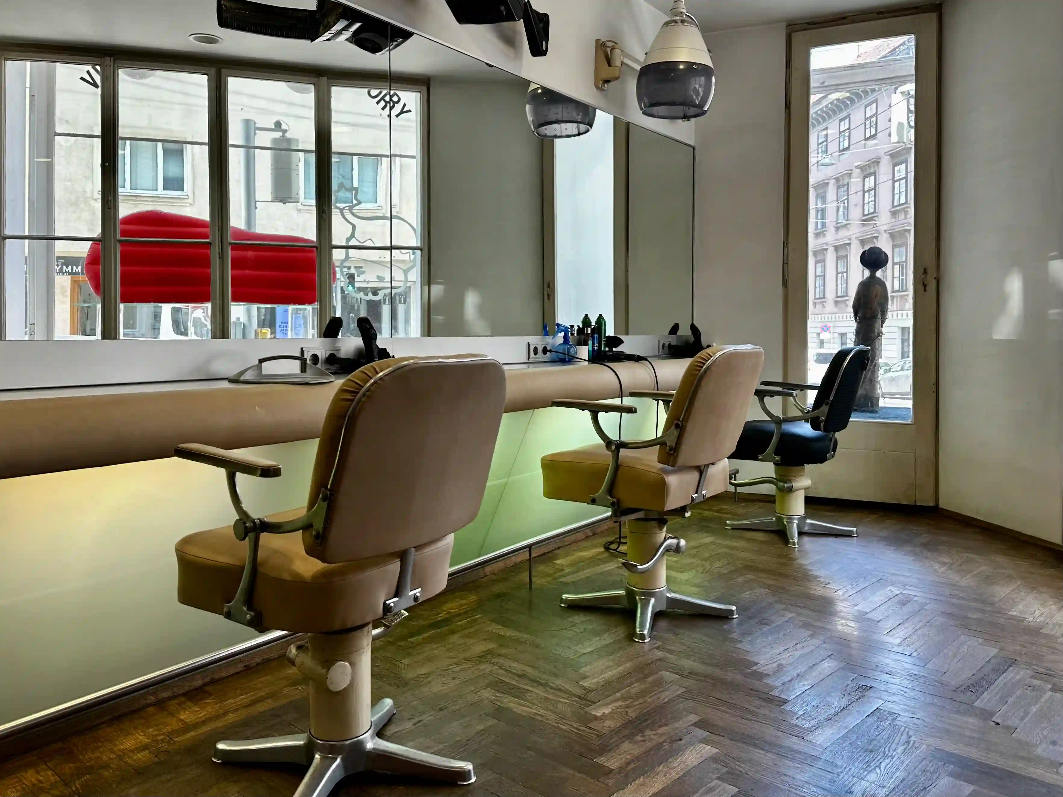 Vintage-Friseurstühle am Fenster der HAIR-FACTORY mit Blick auf die Ungargasse.