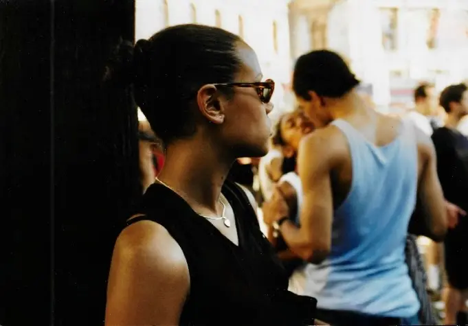 Frau im Profil mit Sonnenbrille bei einem Event in Wien, analog fotografiert, unscharfe Menschen im Hintergrund.