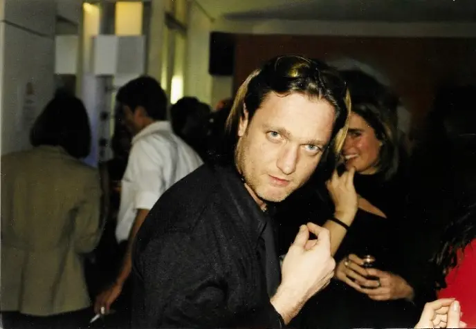 Manfred, Inhaber der HAIR-FACTORY, jung auf einem Event — direkt in die Kamera schauend.